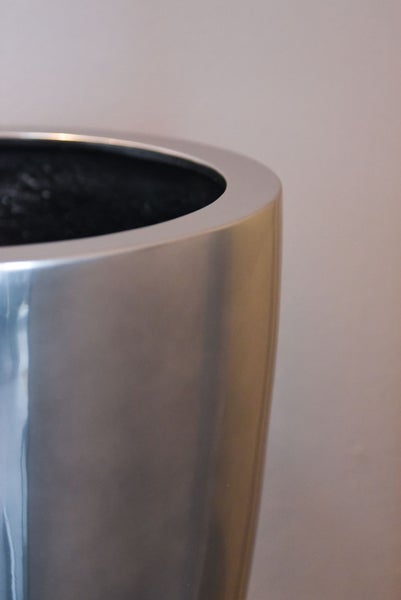 Detailansicht des Randes eines runden Pflanzkübels mit metallischer Oberfläche.