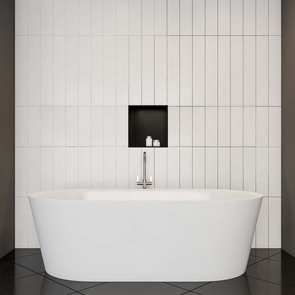 Freistehende Badewanne mit Armatur vor einer Wand mit Fliesen und Regal