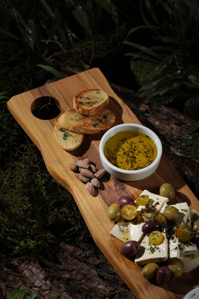 Brot, Mandeln, Olivenöl, Oliven und Käse auf einem Holzbrett