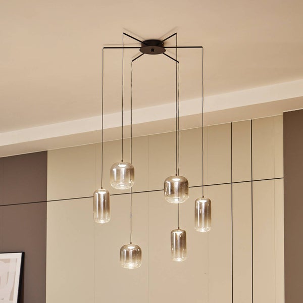 Sechsflammige Hängeleuchte mit unterschiedlich hoch hängenden, zylindrischen Glasschirmen aus Rauchglas an einem schwarzen Deckenbaldachin.