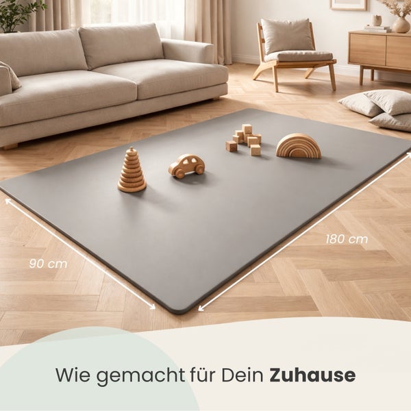 Rechteckige Spielmatte im hellen Wohnzimmer, 90 mal 180 Zentimeter, mit Holzspielzeug auf Parkettboden neben einem Sofa.