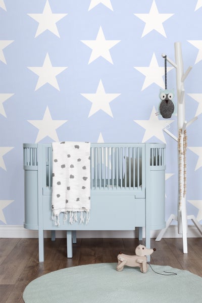 Kinderzimmer mit Gitterbett, Mobile, Spielzeug und Sternentapete