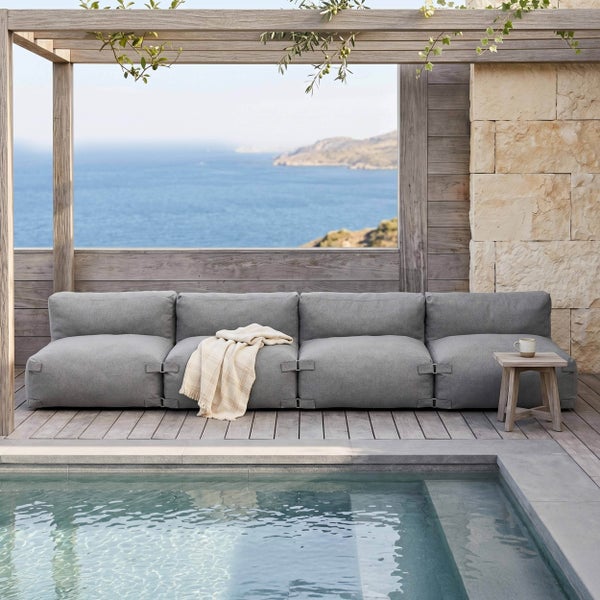 Modernes graues Modulsofa auf einer hellen Holzterrasse am Pool mit Panoramablick auf das Meer.