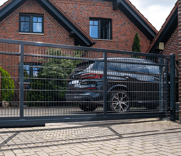 Schiebetor aus Metall mit Auto im Hintergrund vor einem Wohnhaus