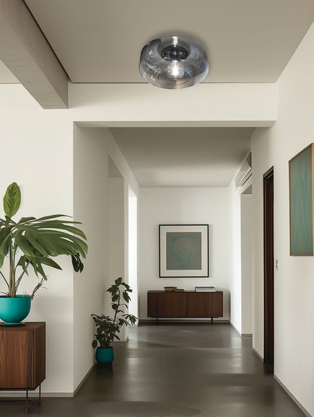 Moderne Deckenleuchte aus rauchfarbenem Glas in einem hellen, minimalistischen Flur mit Holzmöbeln und Zimmerpflanzen.