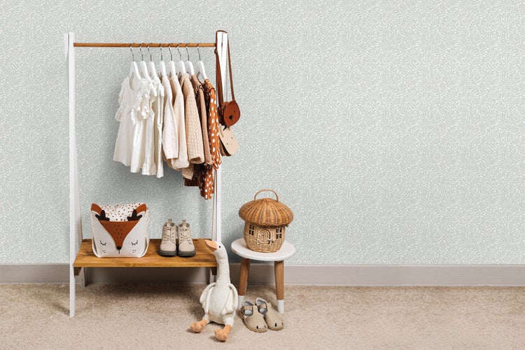 Kinderzimmer mit Kleiderständer, Spielzeug und Tapete mit Blattmuster