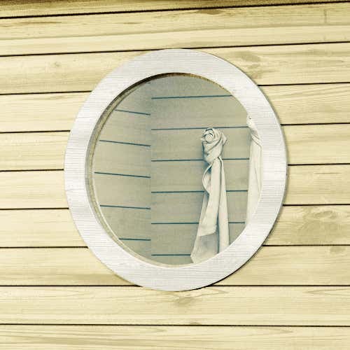 Rundes Saunafenster aus Holz eingebaut in eine Holzwand mit horizontalen Paneelen.