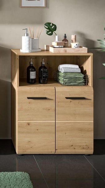 Moderner Badezimmerschrank in Holzoptik mit einem offenen Fach und zwei Türen. Hellbrauner Korpus, schwarze Griffe, dekoriert mit Badutensilien.