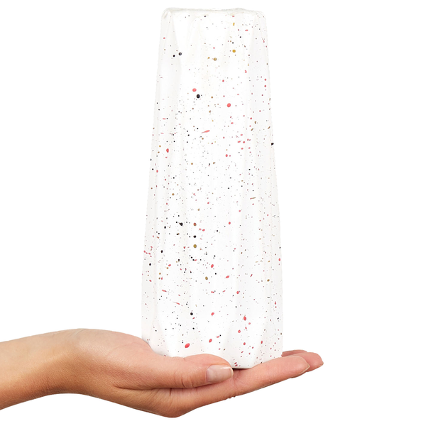 Eine Hand hält eine zylindrische, gesprenkelte Vase als Dekorationsobjekt.