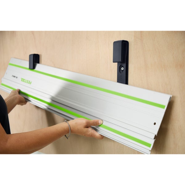 Wandhalterung für Festool Führungsschienen aus Kunststoff, montiert an einer Holzwand, Führungsschiene wird eingehängt.