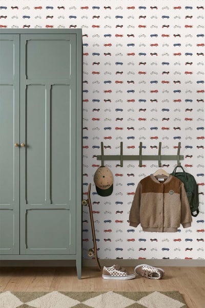 Hell gestaltetes Kinderzimmer mit Tapete mit Oldtimer-Motiven, Holzschreibtisch und Stuhl.