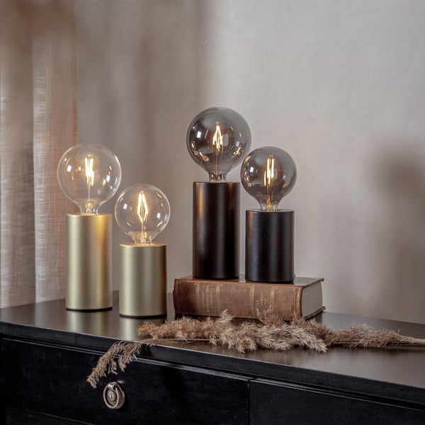 Dekorative Tischleuchten aus Metall und Glühbirnen auf einem schwarzen Schrank