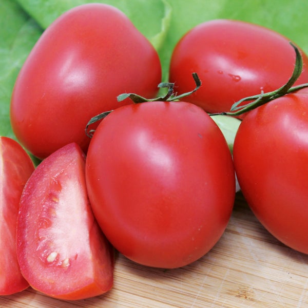 Frische Eiertomaten auf einem Holzbrett, teilweise in Spalten geschnitten.