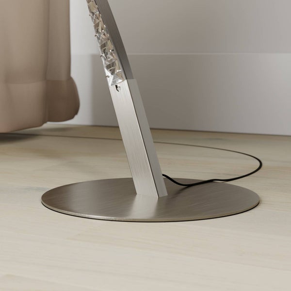 Detailaufnahme eines runden Lampenfusses aus gebuerstetem Metall mit Kristallelementen auf Holzboden.