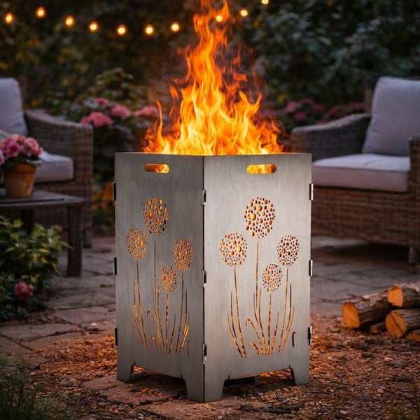 Feuerstelle aus Stahl mit ausgeschnittenem Löwenzahnmuster und brennendem Feuer im Garten