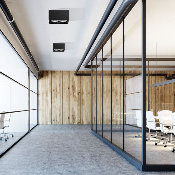 Büroraum mit Holzwand, Glaswänden, Deckenleuchten und Konferenztisch.