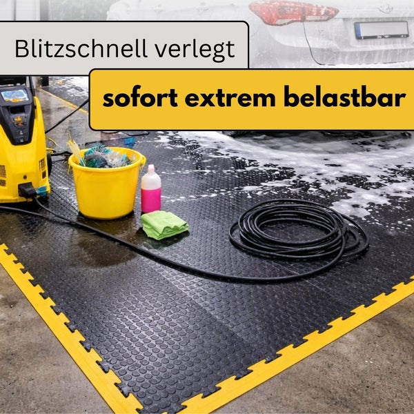 Schwarze ineinandergreifende Garagen-Bodenfliesen mit Noppenstruktur und gelben Abschlusskanten in einem Waschbereich mit Hochdruckreiniger.