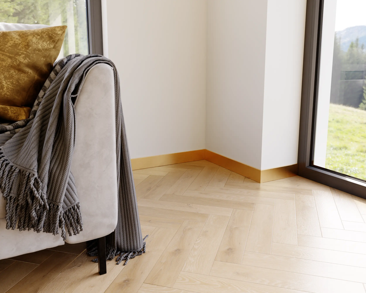 Detailaufnahme eines Zimmers mit Parkettboden und einem Teil eines Sofas mit Kissen und Decke.