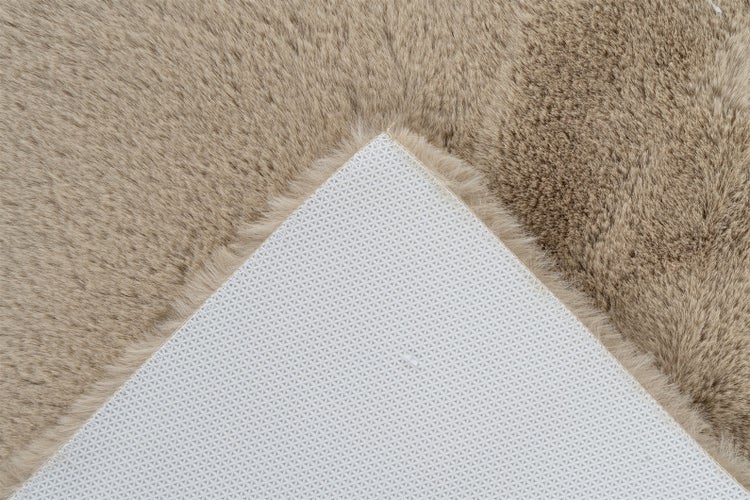 Nahaufnahme eines flauschigen Teppichs mit umgeknickter Ecke, die die rutschfeste Unterseite mit strukturierter Oberfläche zeigt.