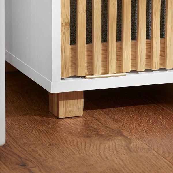 Detailansicht eines weißen Schranks mit Bambusfront und Füßen auf einem Holzboden