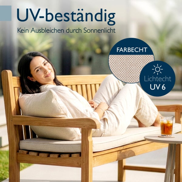 Frau auf einer Holzgartenbank mit UV-beständigen und lichtechten Sitzpolstern, die vor dem Ausbleichen durch Sonnenlicht geschützt sind.