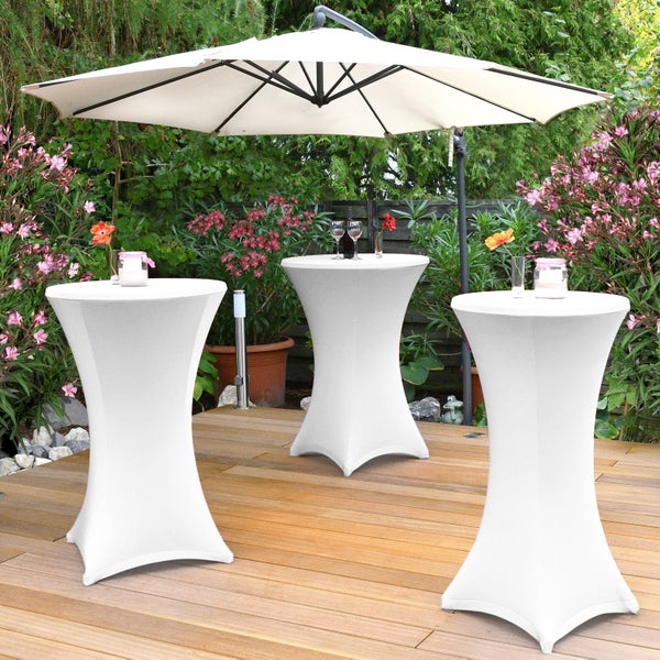 Drei Stehtische mit Hussen und ein Sonnenschirm auf einer Terrasse mit Gartenbegrünung