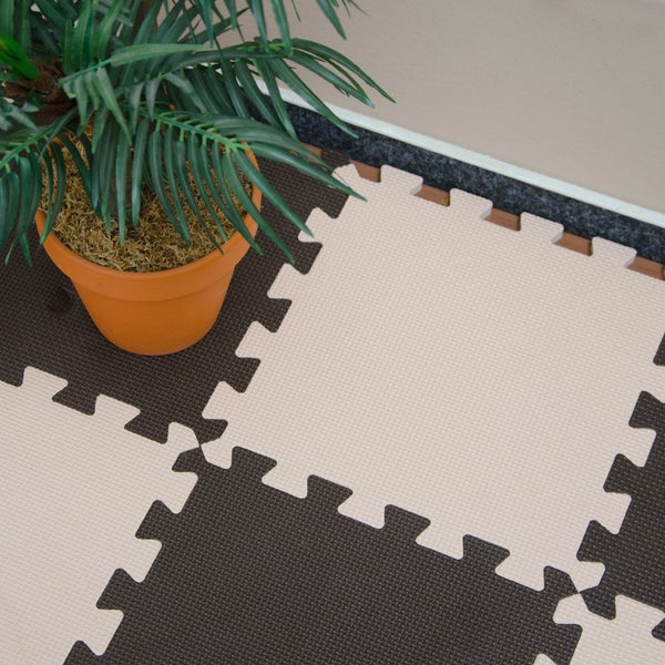 Puzzlematte aus Schaumstoff als Bodenbelag im Schachbrettmuster mit einer Pflanze im Topf