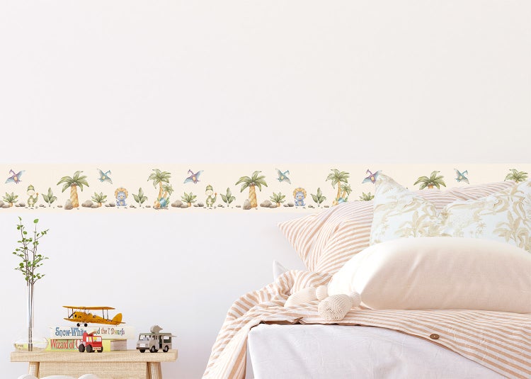 Selbstklebende Tapetenbordüre mit Dinosaurier- und Palmenmotiven im Aquarellstil in einem hellen Kinderzimmer über einem Bett.