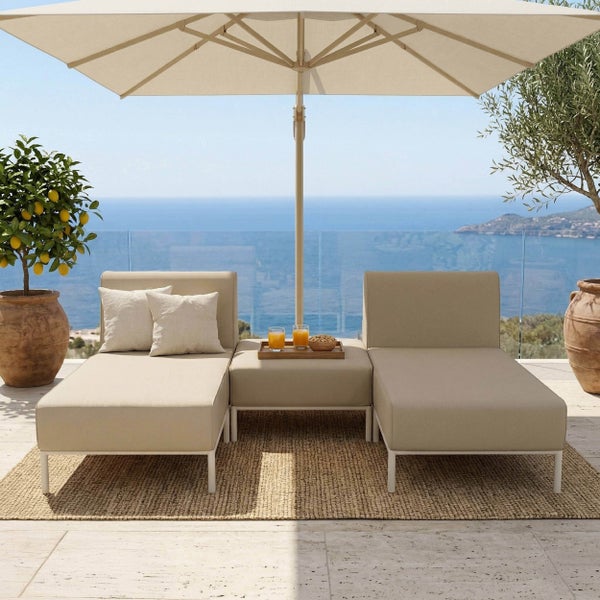Garten-Loungeset mit zwei Liegen, Hocker und großem Sonnenschirm auf einem Balkon mit Meerblick und Topfpflanzen.