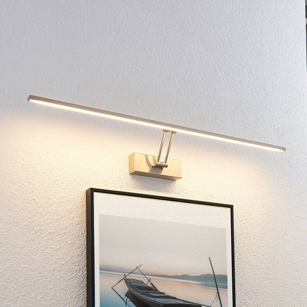 Schlanke LED Bilderleuchte aus Metall an einer Wand über einem gerahmten Bild montiert, mit Lichtschein nach unten.