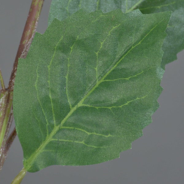 Nahaufnahme eines grünen künstlichen Blattes mit gezackten Rändern und sichtbaren Blattadern an einem Stängel.