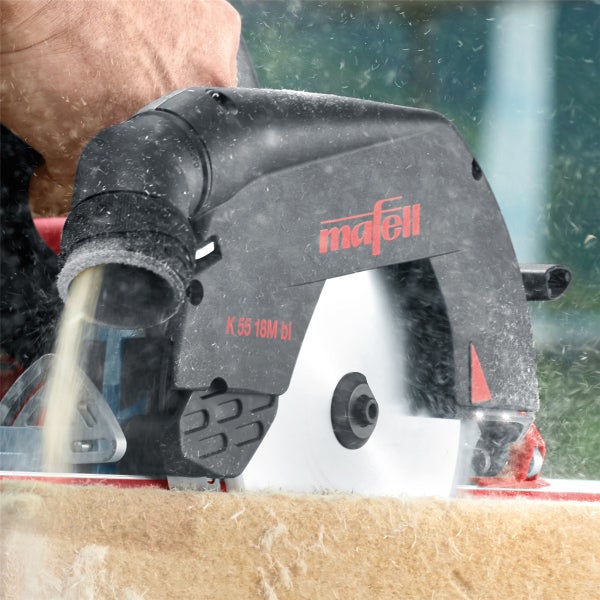 Handgeführte Mafell Handkreissäge K 55 18M bl bei der Arbeit mit Spanflug beim Sägen einer Holzplatte.
