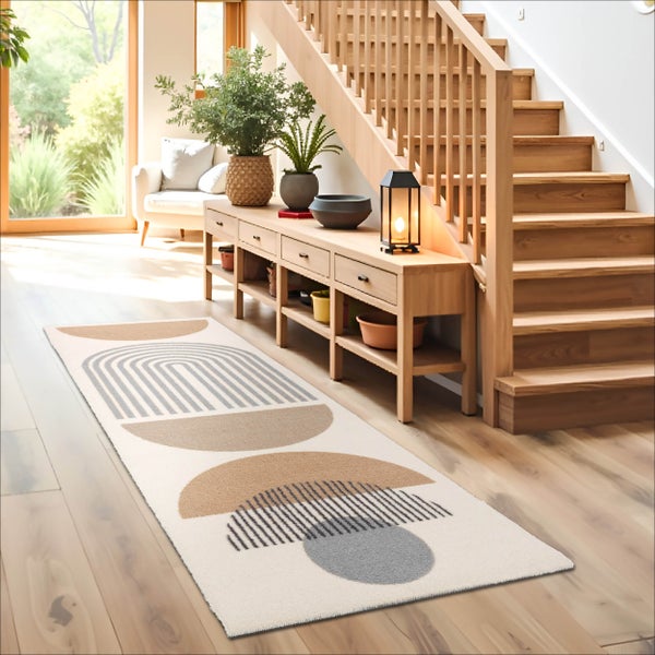 Moderner Läufer mit geometrischem Muster auf einem Holzfußboden in einem hellen Flur neben einer Holztreppe.