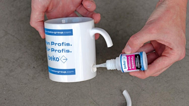 Eine Person klebt mit Sekundenkleber einen abgebrochenen Tassenhenkel an eine Tasse.