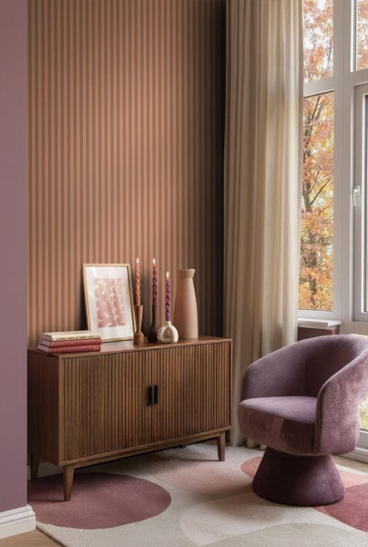 Wohnraum mit gestreifter Tapete, Holzkommode, Dekoration und Sessel