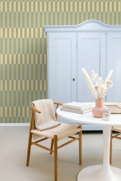 Helle Raumszene mit geometrischer Tapete mit vertikalen Streifen, Schrank, Rundtisch und Holzstuhl mit Decke.