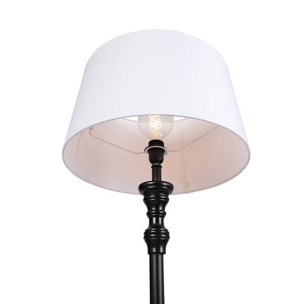 Leuchte mit weißem Stoffschirm und schwarzem, verziertem Metallschaft, inklusive sichtbarem Leuchtmittel.