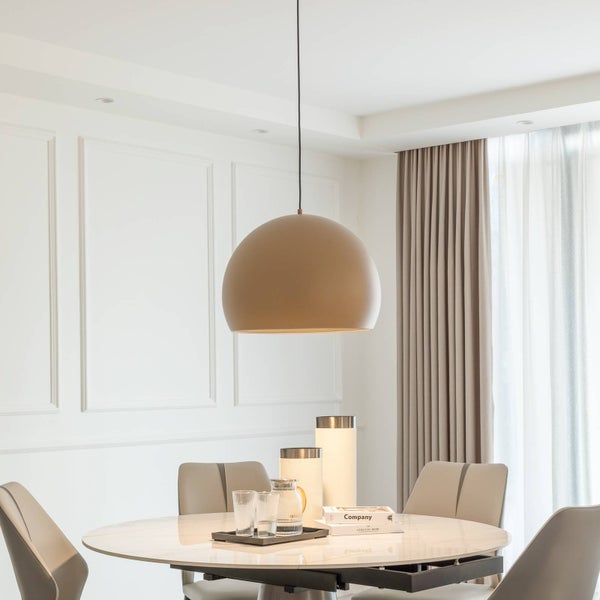 Große halbkugelförmige Pendelleuchte über einem runden Marmor-Esstisch in einem hellen, modernen Esszimmer mit Wandpaneelen und Vorhängen.
