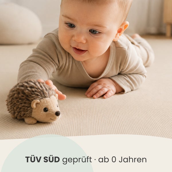 Ein Baby spielt auf dem Boden mit einem Plüschigel, der TÜV SÜD geprüft ist und für Kinder ab null Jahren geeignet ist.
