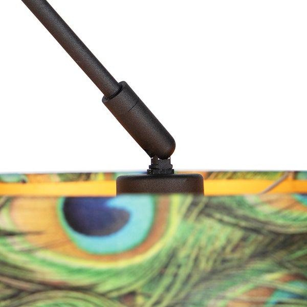 Nahaufnahme eines schwarzen Lampenarms aus Metall mit Gelenk an einem Lampenschirm mit Pfauenfedermuster.