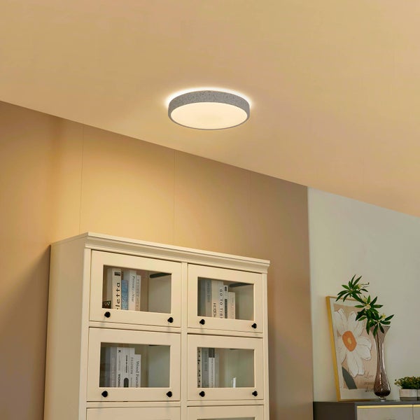 Runde Deckenleuchte mit Rand in Betonoptik, montiert in einem hellen modernen Wohnraum über einem weißen Schrank.