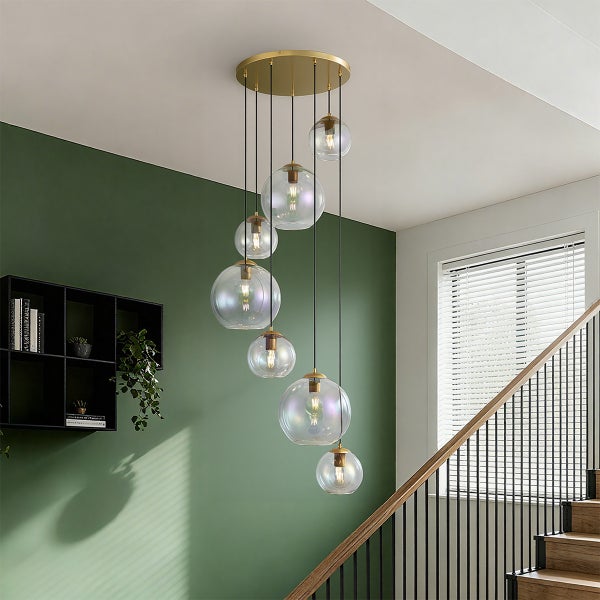 Moderne Treppenhaus-Hängeleuchte mit sieben transparenten Kugeln und goldfarbener Deckenbefestigung.
