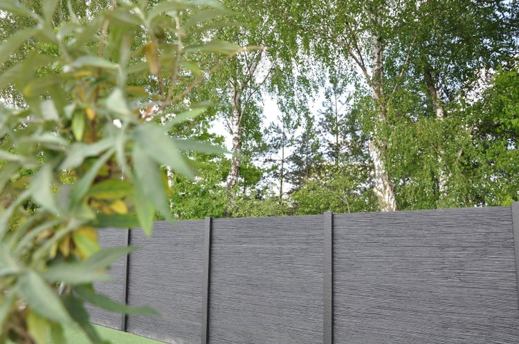 Gartenansicht mit grauer Holzzaunstruktur und Bäumen