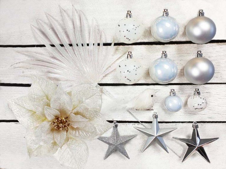 Weihnachtsdekoration Set mit Kugeln, Sternen, Kunstblume und Vogel auf hellem Holzgrund.