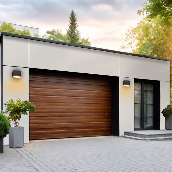 Moderne Garage mit Holztor, Außenbeleuchtung und gepflasterter Einfahrt.