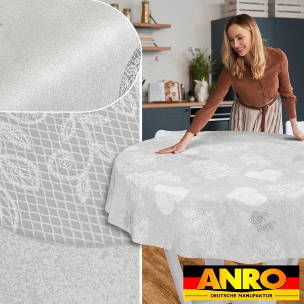 Rundes Wachstuch mit Herz- und Blumenmuster, auf einem Tisch in einer Küche ausgelegt, Detailansicht der Oberflächenstruktur, ANRO Logo.