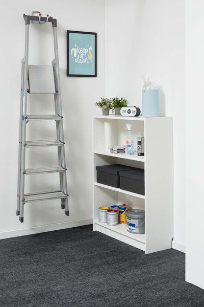 Silberne Aluminium-Stufenleiter an der Wand neben einem weißen Regal mit Reinigungsmitteln und Farbdosen in einem hellen, organisierten Raum.
