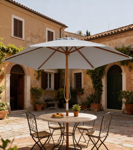 Großer Sonnenschirm mit Holzgestell über einer Sitzgruppe in einem mediterranen Innenhof mit Steinpflaster und Topfpflanzen.
