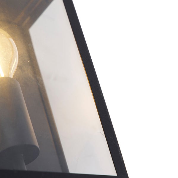 Nahaufnahme einer Wandleuchte aus Metall mit Glaseinsatz und leuchtendem Leuchtmittel.