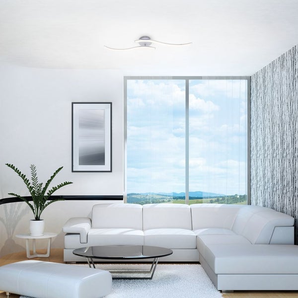 Moderne LED-Deckenleuchte mit wellenförmigen Armen in einem hellen, organisierten Wohnzimmer mit weißem Ecksofa und großem Fenster.